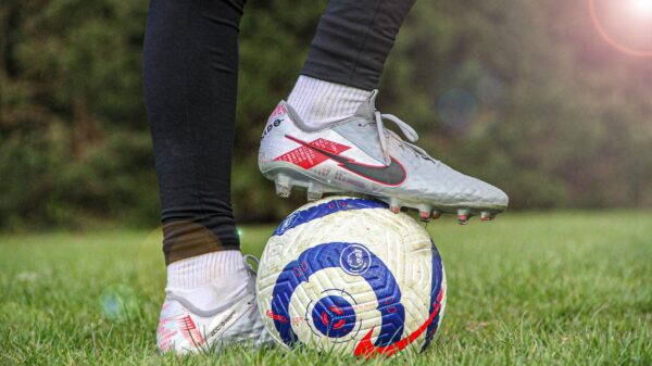 person in black pants wearing white and red nike soccer cleats