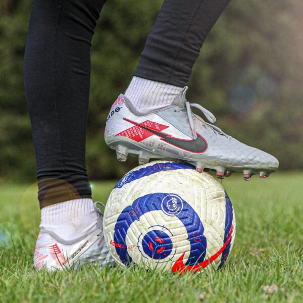 person in black pants wearing white and red nike soccer cleats