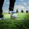 person in black pants and blue and white nike soccer ball on green grass field during