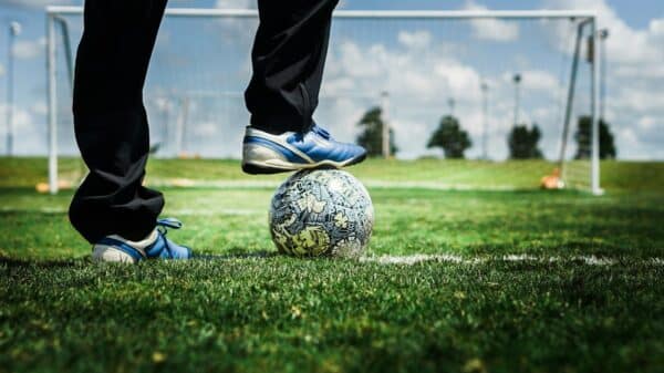 person in black pants and blue and white nike soccer ball on green grass field during