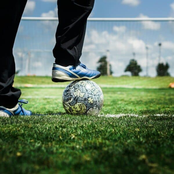 person in black pants and blue and white nike soccer ball on green grass field during