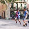 two boy's playing soccer near building during daytime