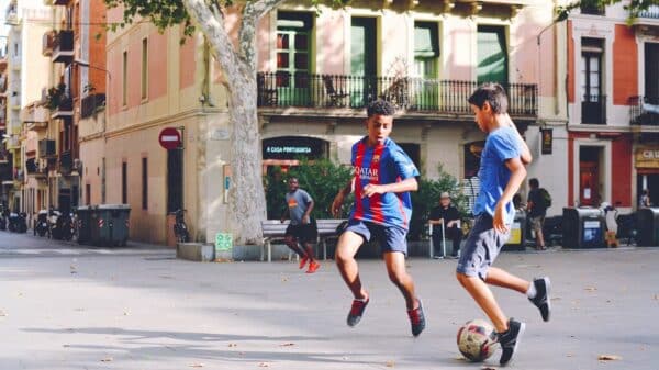 two boy's playing soccer near building during daytime