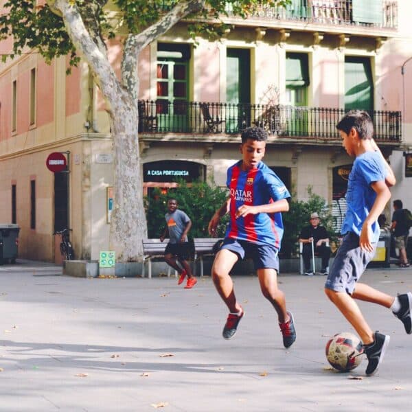 two boy's playing soccer near building during daytime